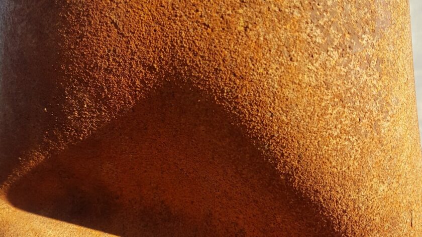 Rostgelbes Stahlrohr mit dreieckiger Einkerbung, die Schatten erzeugt. Fotodruck auf Dibond oder Forex in verschiedenen Formaten.