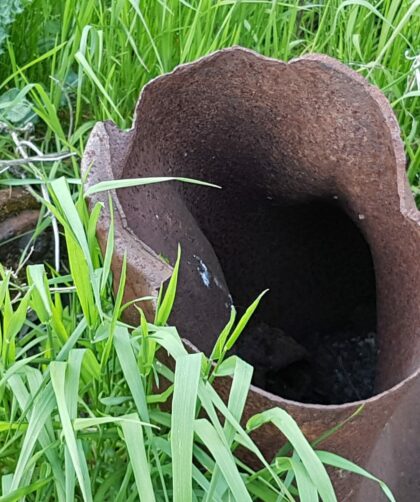 offenes rostiges Stahlrohr mit unebenem Ende zwischen Pflanzen. Fotodruck auf Dibond oder Forex in verschiedenen Formaten.