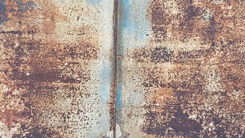 Stahltür mit blauen Farbresten. Schweißnaht, Rostmarken und Türscharnier. Fotodruck auf Dibond oder Forex in verschiedenen Formaten.