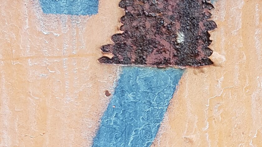 Rostige Stahlplatte mit markanter Rostmarke und blauer Zahl 7 auf orange-gelbem Untergrund. Fotodruck auf Dibond oder Forex in diversen Formaten.